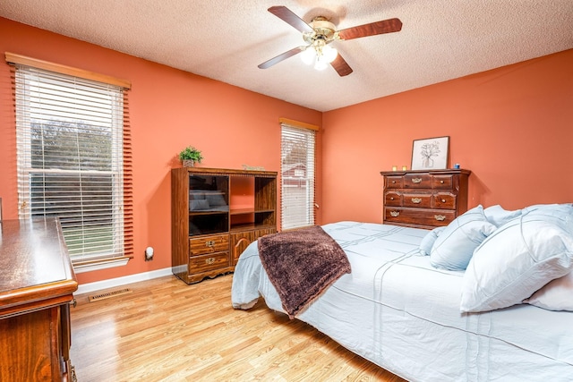 bedroom featuring visible vents, a textured ceiling, light wood finished floors, and multiple windows