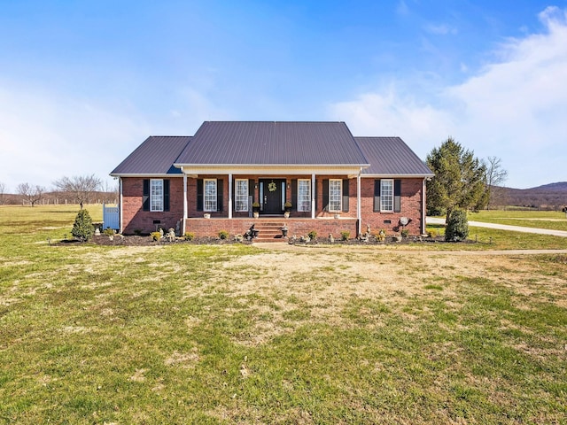 view of front of home featuring covered porch, a front yard, metal roof, and brick siding