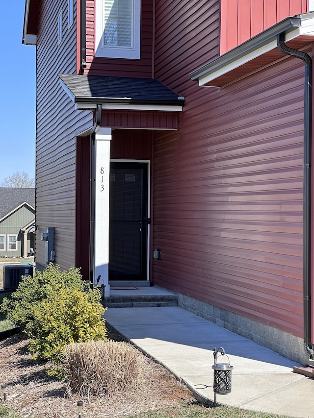 property entrance with a shingled roof, central AC, and board and batten siding