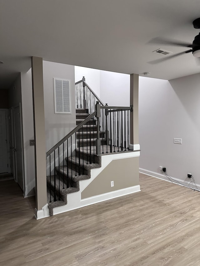 stairs featuring a ceiling fan, baseboards, visible vents, and wood finished floors