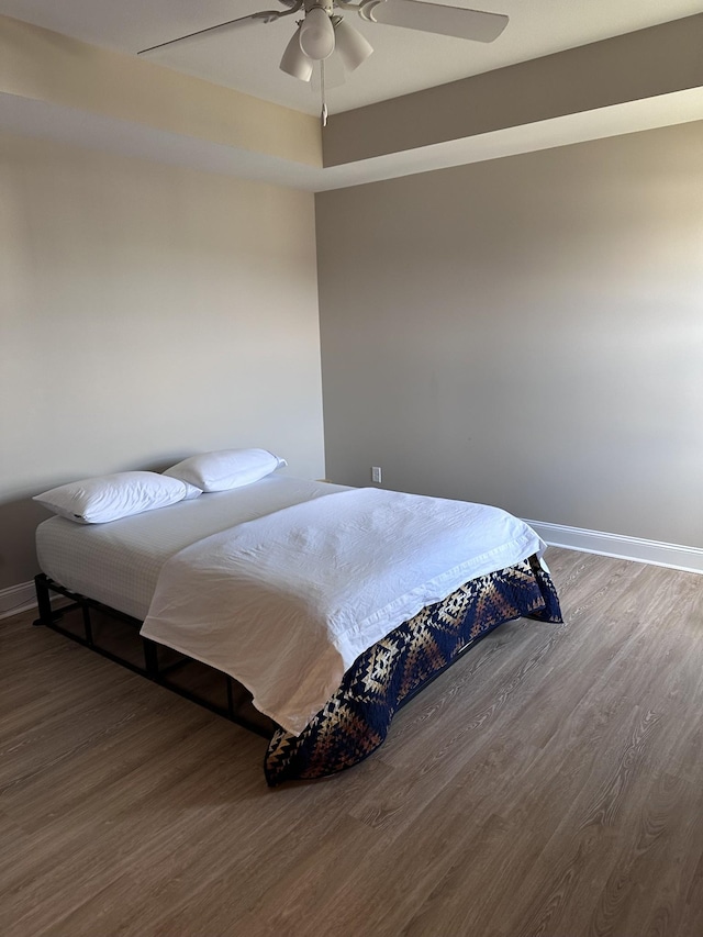 bedroom with ceiling fan, baseboards, and wood finished floors