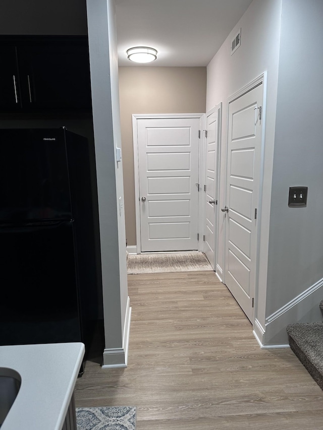 hall with light wood-style floors, visible vents, and baseboards