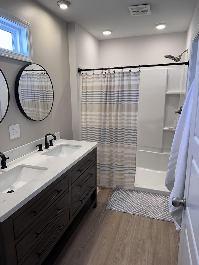 full bath featuring wood finished floors, a sink, visible vents, and a shower with curtain