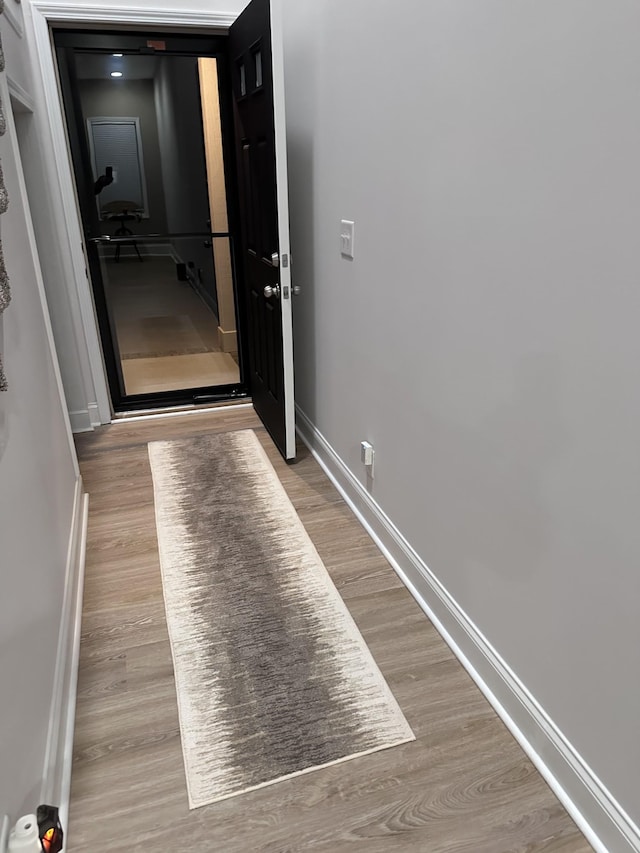 corridor featuring baseboards and wood finished floors