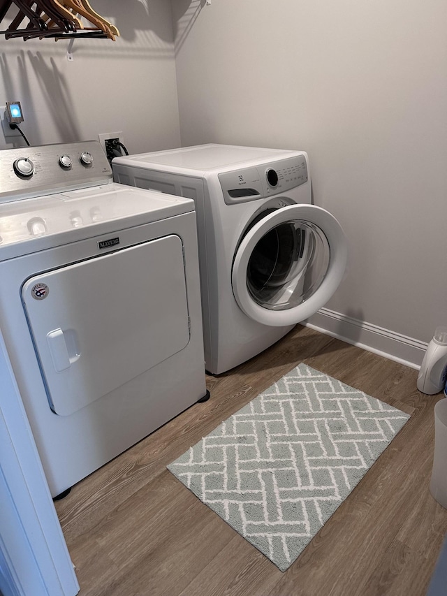 laundry area featuring laundry area, baseboards, wood finished floors, and washing machine and clothes dryer