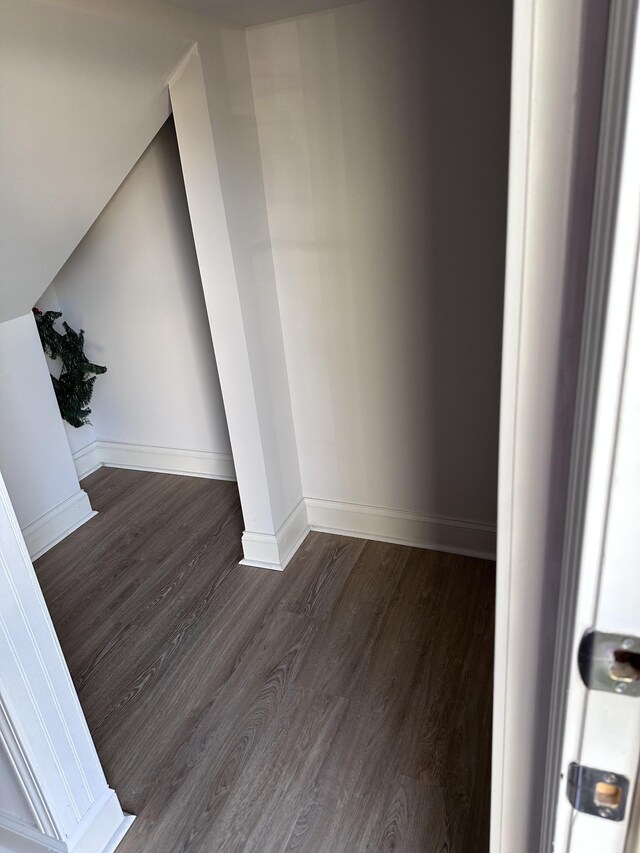 interior space with vaulted ceiling, dark wood finished floors, and baseboards