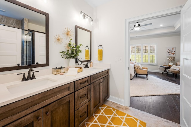 ensuite bathroom featuring a sink, double vanity, a raised ceiling, and connected bathroom