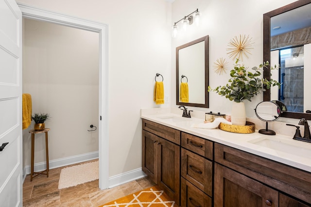 full bathroom featuring double vanity, baseboards, and a sink