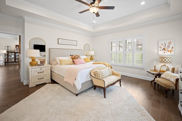 bedroom with dark wood-style floors, baseboards, a tray ceiling, and crown molding