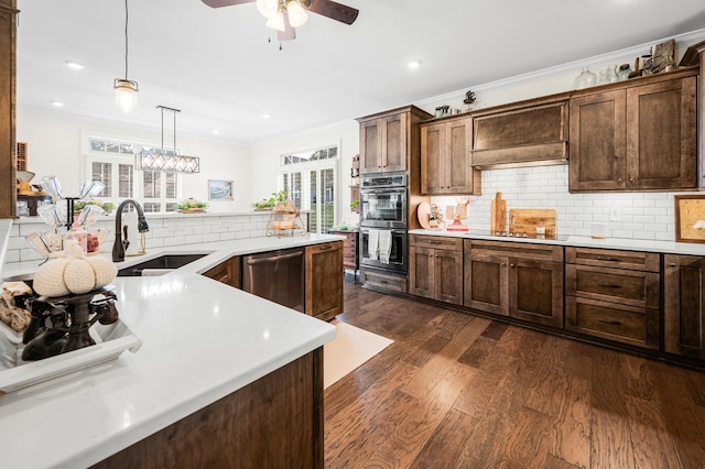 kitchen with a sink, light countertops, ornamental molding, appliances with stainless steel finishes, and dark wood finished floors