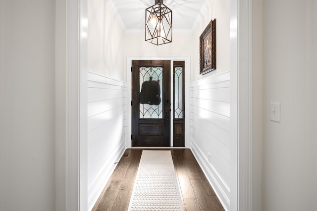 doorway with a notable chandelier, crown molding, and dark wood-style flooring