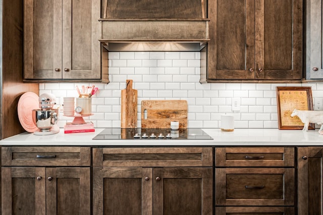 kitchen with black electric stovetop, light countertops, backsplash, and dark brown cabinets