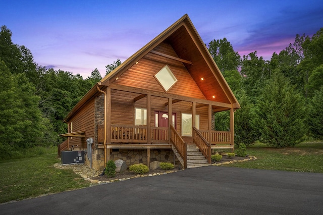 view of front of house with covered porch, central AC unit, and a yard