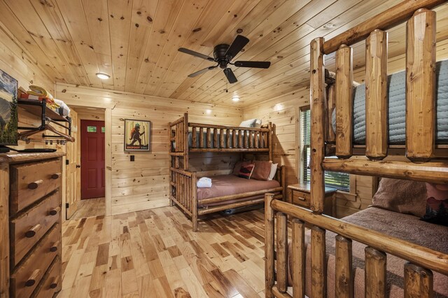 bedroom with light wood finished floors, wood walls, and wooden ceiling