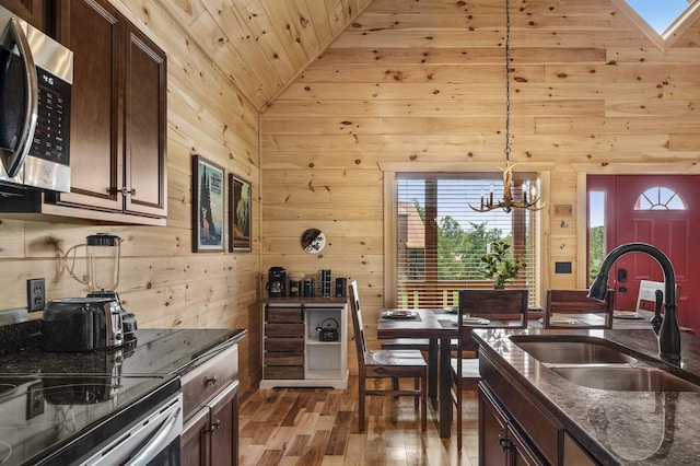 kitchen featuring wood finished floors, a sink, dark brown cabinets, electric range oven, and stainless steel microwave