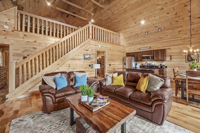 living area featuring stairs, wood walls, wood ceiling, and an inviting chandelier