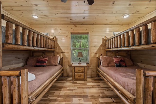 bedroom with light wood-style floors, wood ceiling, and wood walls