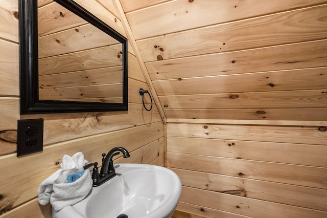 bathroom featuring wood walls and a sink