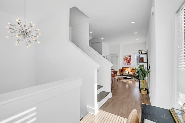 foyer with stairs, recessed lighting, wood finished floors, and an inviting chandelier