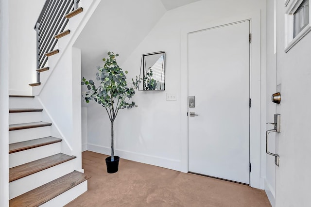 entrance foyer featuring concrete floors, stairway, and baseboards