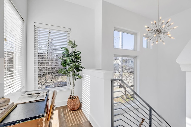 interior space with a chandelier, wood finished floors, a towering ceiling, an upstairs landing, and baseboards