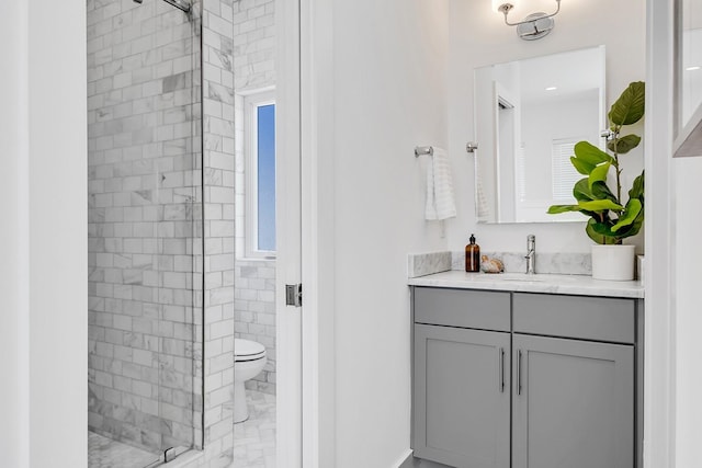 bathroom featuring toilet, a tile shower, and vanity