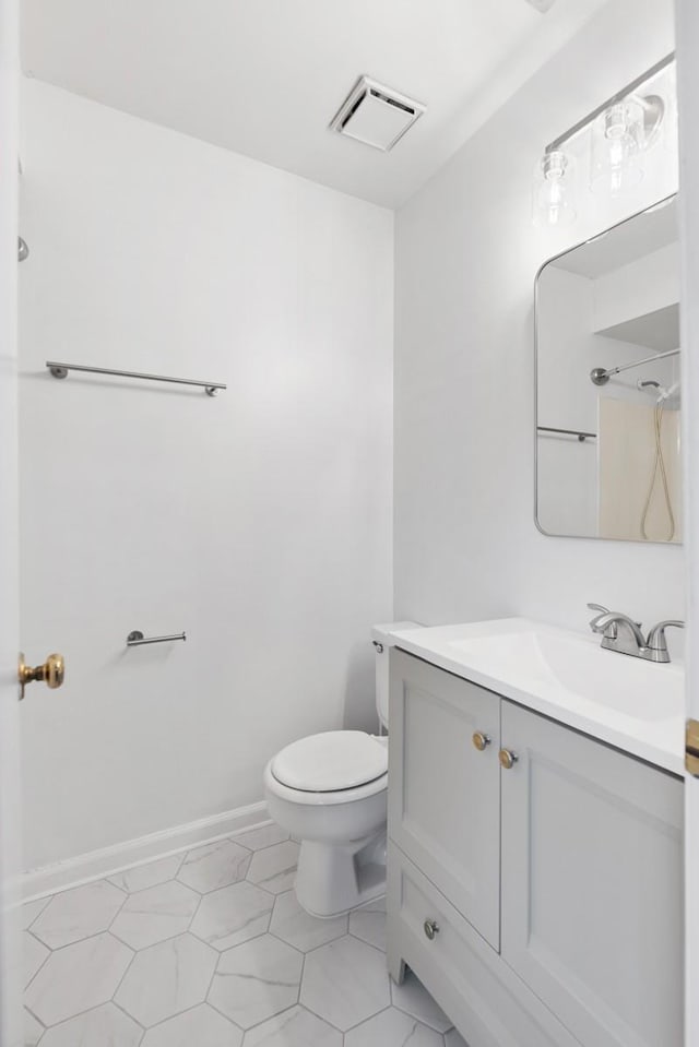 bathroom featuring toilet, vanity, visible vents, baseboards, and walk in shower