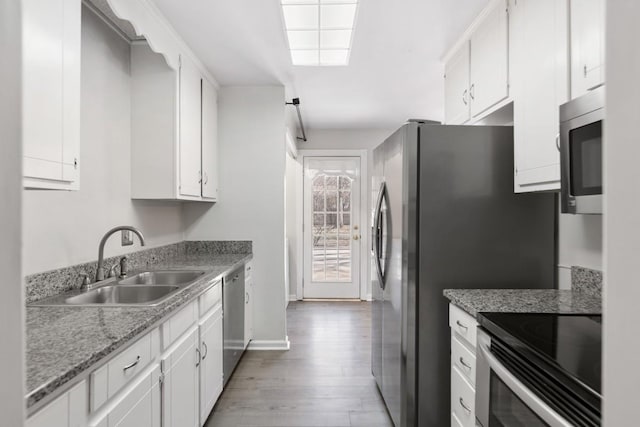 kitchen featuring stainless steel appliances, light wood-type flooring, white cabinetry, and a sink