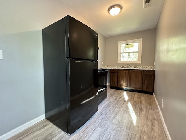 kitchen with light wood-style floors, freestanding refrigerator, visible vents, and baseboards