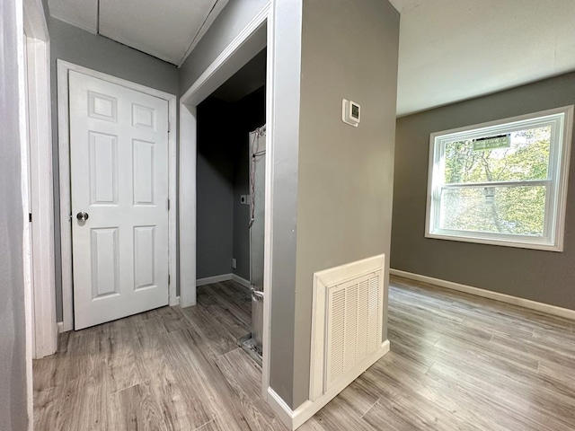 hall featuring light wood-style floors, visible vents, and baseboards