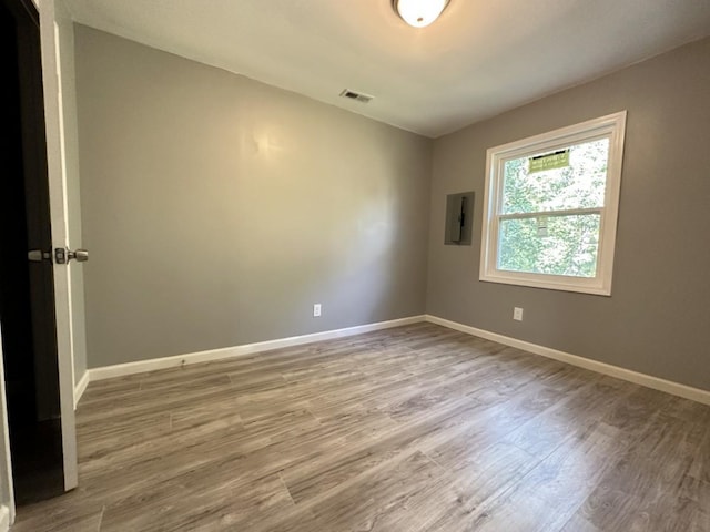 spare room with visible vents, wood finished floors, electric panel, and baseboards