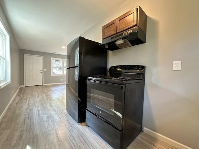 kitchen with baseboards, light wood-style flooring, brown cabinets, under cabinet range hood, and black range with electric cooktop