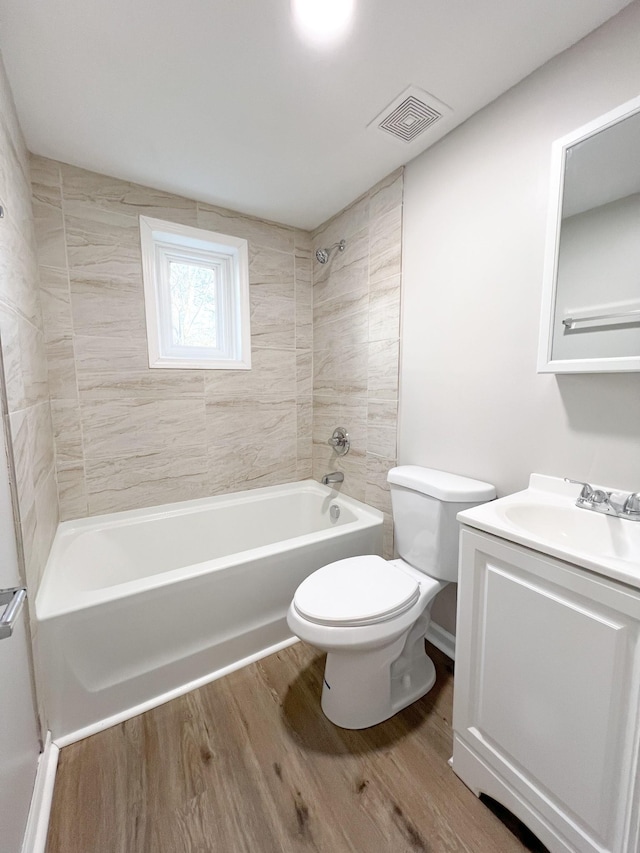 full bath with shower / tub combination, toilet, wood finished floors, vanity, and visible vents