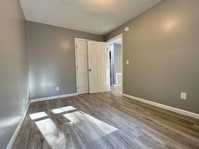 spare room with visible vents, baseboards, and wood finished floors