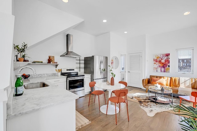 kitchen featuring light wood finished floors, open shelves, stainless steel appliances, a sink, and wall chimney range hood