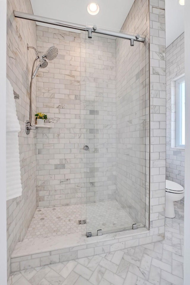 full bathroom featuring toilet, marble finish floor, and a shower stall