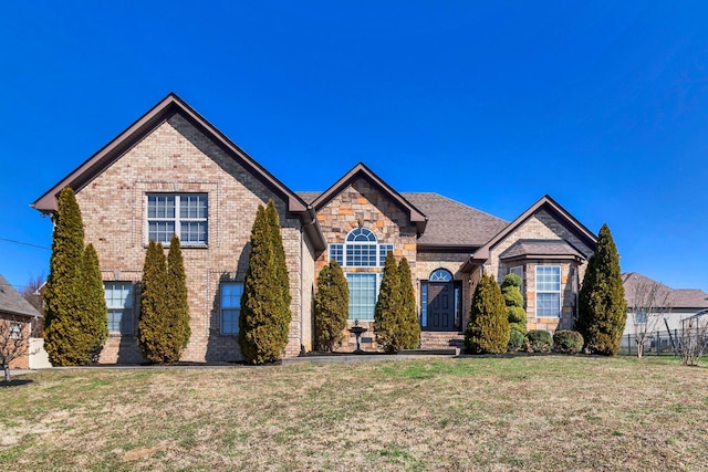 view of front of house with a front yard, brick siding, and stone siding