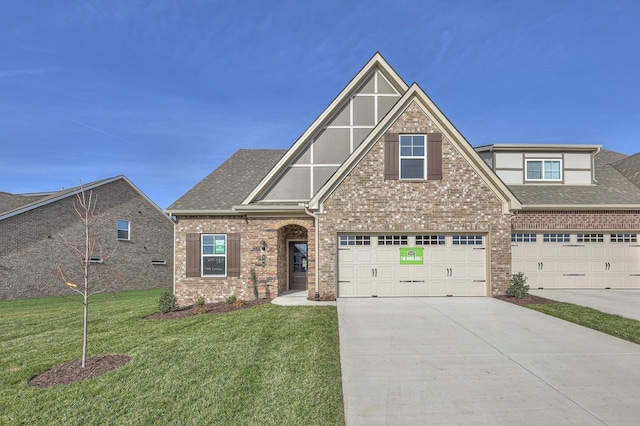 view of front facade with brick siding, a shingled roof, an attached garage, a front yard, and driveway