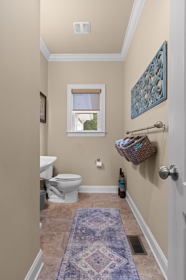 half bathroom with baseboards, visible vents, crown molding, and toilet