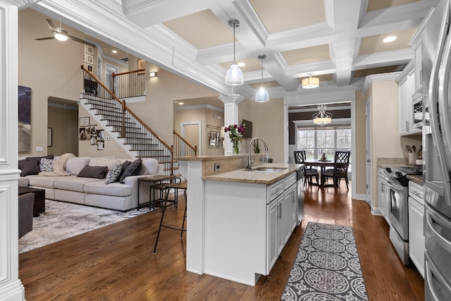 kitchen featuring dark wood-style floors, stainless steel appliances, open floor plan, a sink, and a kitchen breakfast bar