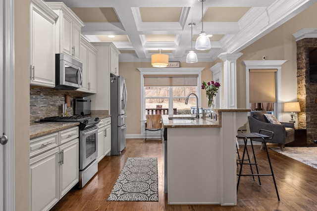 kitchen with an island with sink, a breakfast bar, dark wood-style flooring, stainless steel appliances, and a sink