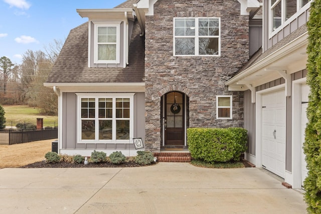 view of front of house with a garage, stone siding, a shingled roof, and concrete driveway