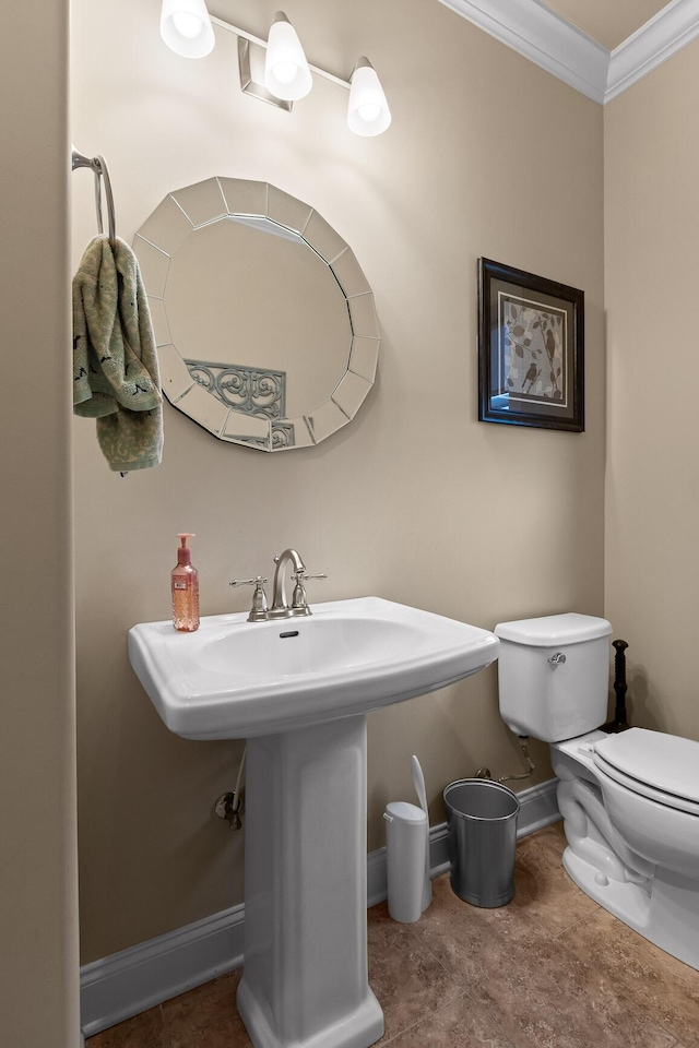 half bath with toilet, baseboards, ornamental molding, and a sink