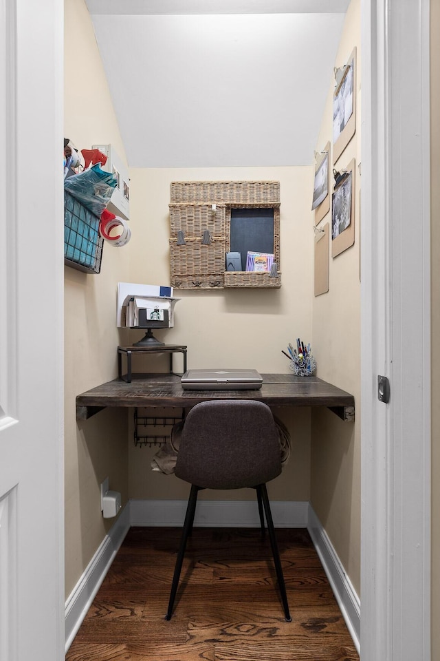 office with dark wood finished floors, built in desk, and baseboards