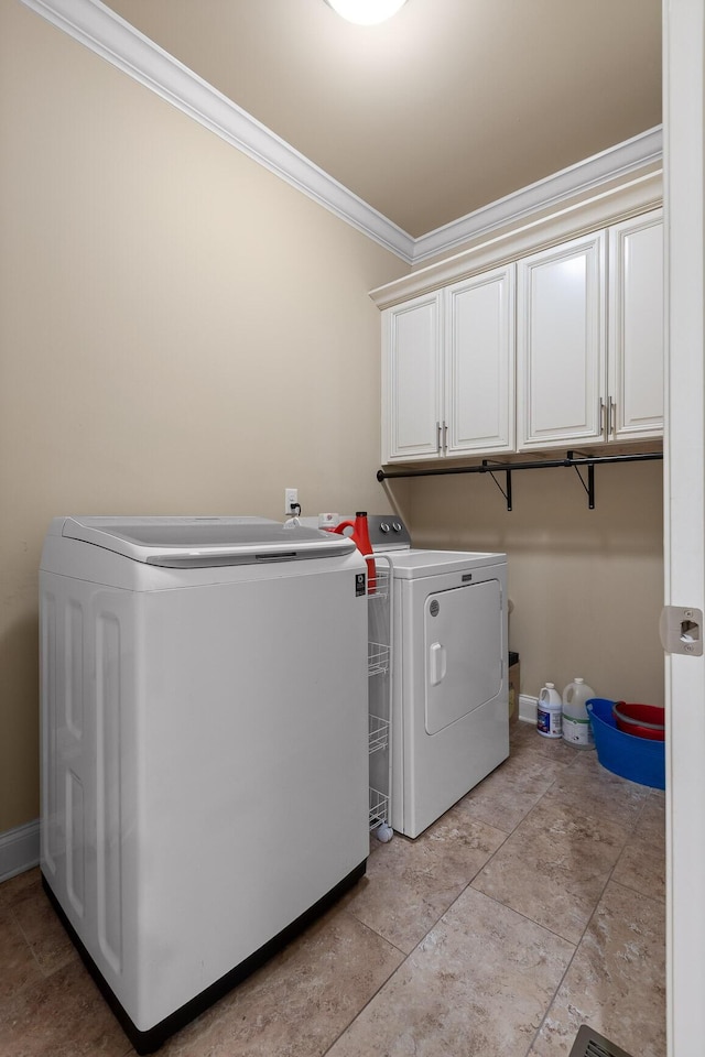 clothes washing area with ornamental molding, washer and clothes dryer, cabinet space, and baseboards