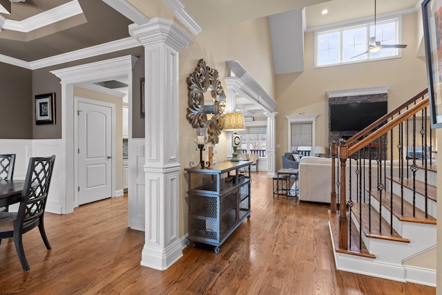 foyer entrance with decorative columns, stairs, crown molding, and wood finished floors