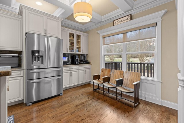 kitchen featuring stainless steel fridge, white cabinets, glass insert cabinets, ornamental molding, and wood finished floors