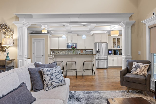 living room featuring beam ceiling, coffered ceiling, decorative columns, and wood finished floors