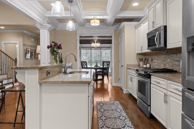 kitchen featuring appliances with stainless steel finishes, a sink, white cabinets, and a kitchen breakfast bar