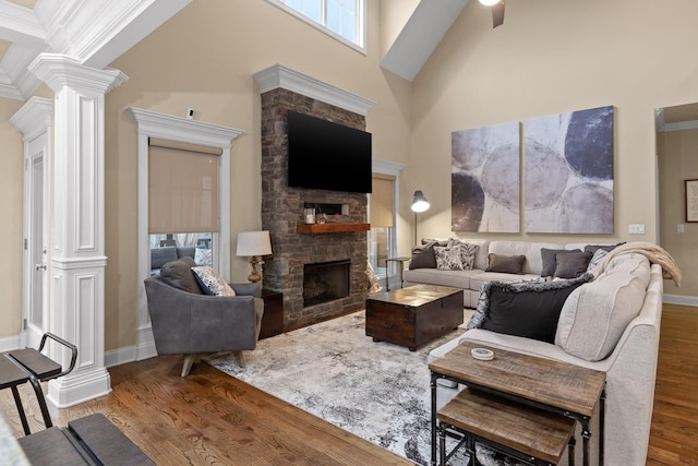 living room featuring a high ceiling, plenty of natural light, ornate columns, and wood finished floors